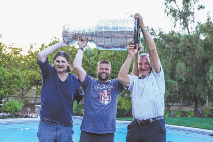 3 people hold Stanley Cup