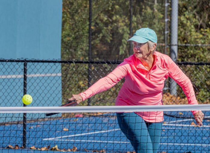 pickleball player strikes ball