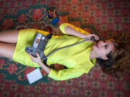 woman in a yellow dress speaks on a landline