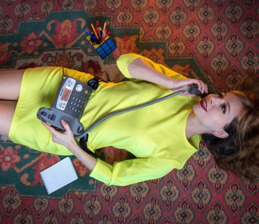 woman in a yellow dress speaks on a landline
