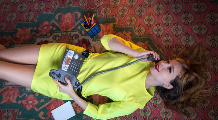 woman in a yellow dress speaks on a landline