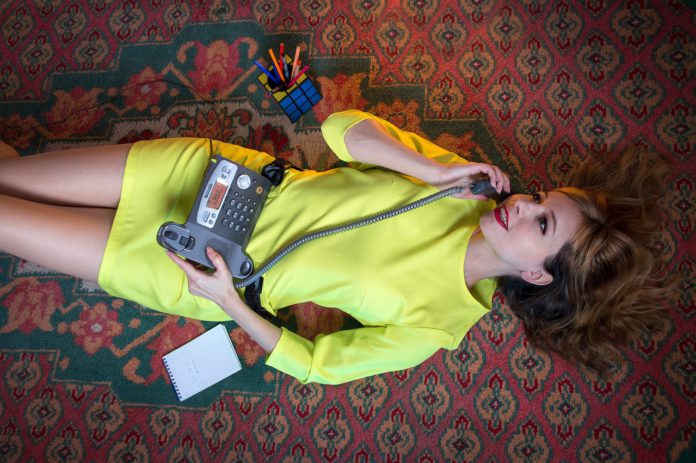 woman in a yellow dress speaks on a landline