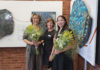 Three people standing in front of artwork