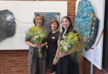 Three people standing in front of artwork