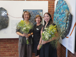 Three people standing in front of artwork