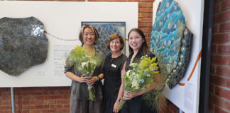 Three people standing in front of artwork