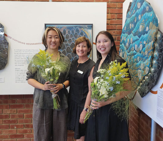 Three people standing in front of artwork