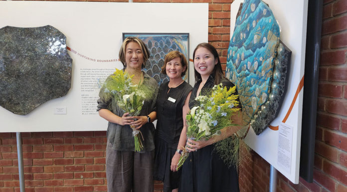 Three people standing in front of artwork