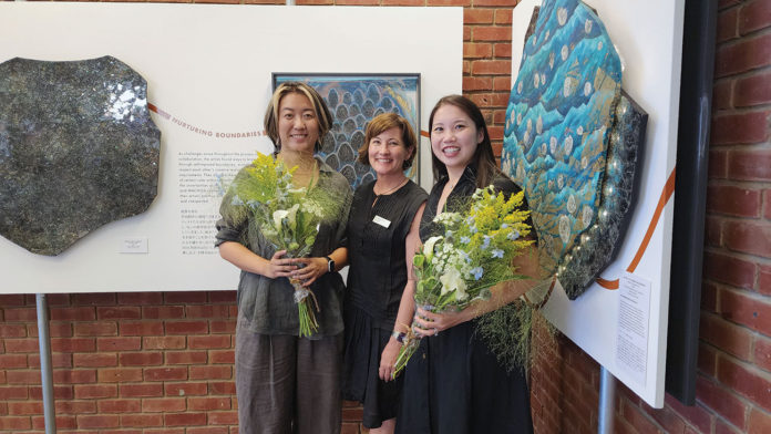 Three people standing in front of artwork