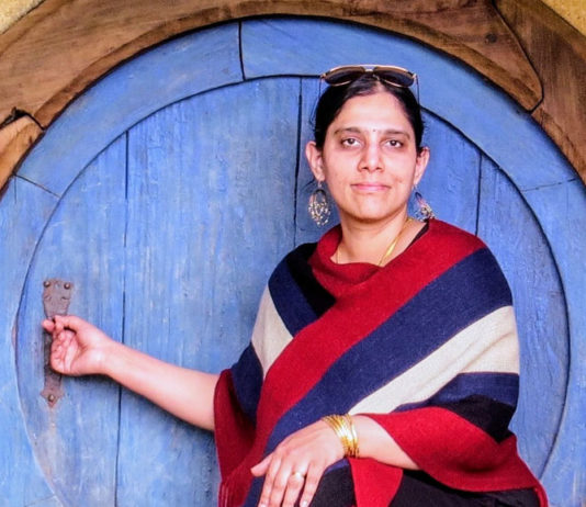 Photo of a woman in front of a round blue door
