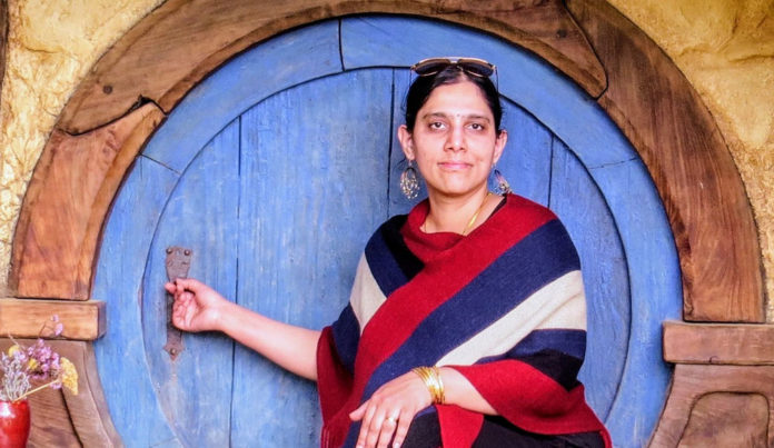Photo of a woman in front of a round blue door