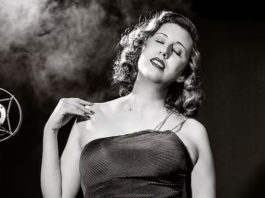 Black-and-white photo of woman in an evening gown by an old-fashioned microphone