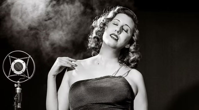 Black-and-white photo of woman in an evening gown by an old-fashioned microphone