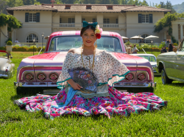 3rd Annual Lowrider Art Showcase happening this weekend in Saratoga woman in pink dress on lawn in front of a car