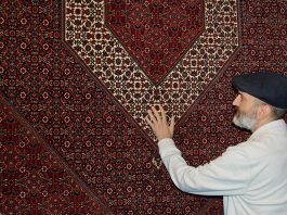 Babak Falasiri with maroon Persian rug at his shop