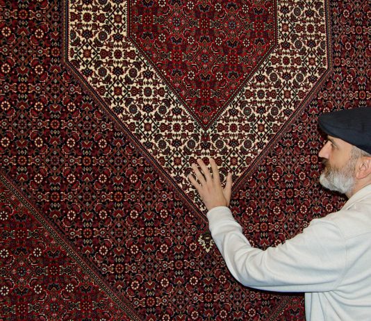 Babak Falasiri with maroon Persian rug at his shop