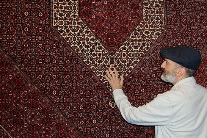 Babak Falasiri with maroon Persian rug at his shop
