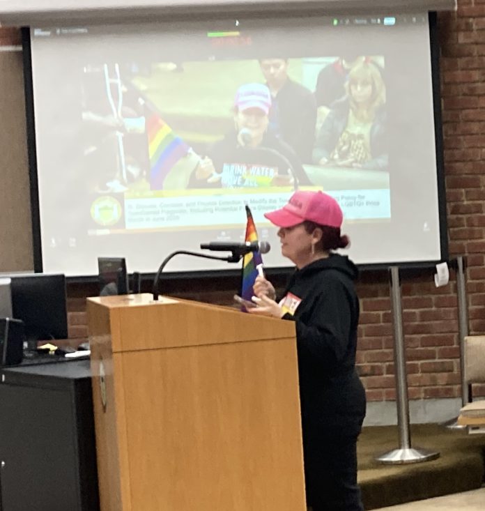 From Saratoga with flag woman with rainbow flag during public comment in Los Gatos