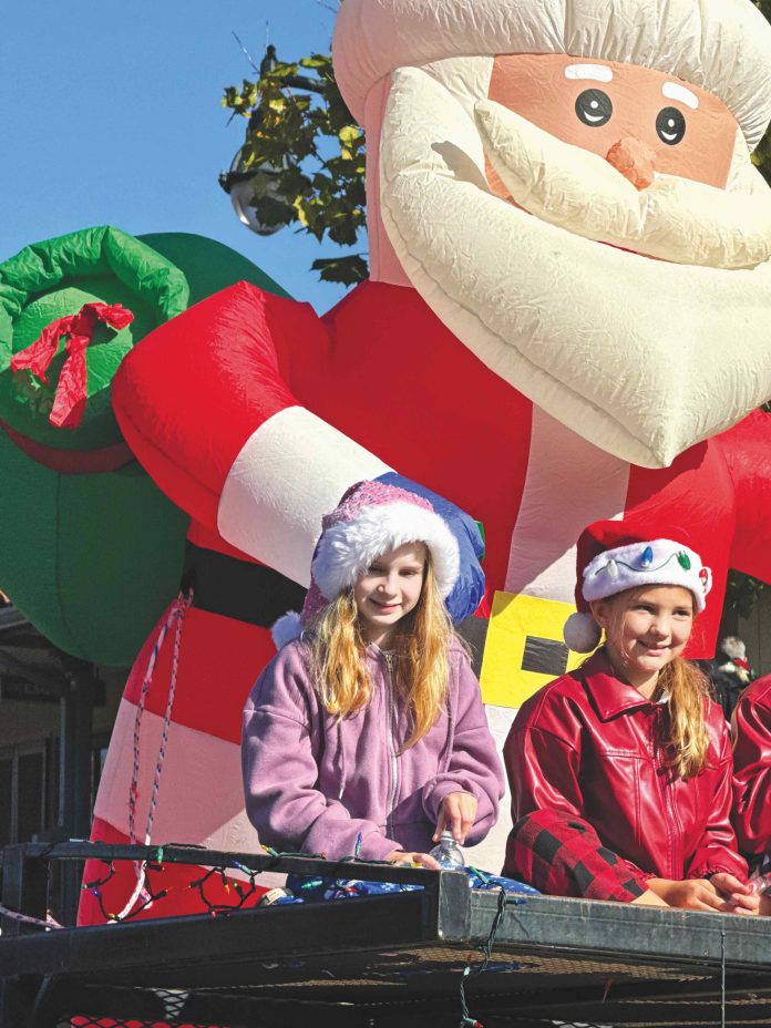 Inflatable Santa in parade1 two kids on a float with an inflatable Santa behind them
