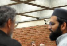 Town Attorney finds the initial conditions for mosque were discriminatory two commissioners speak at break while two Muslim attendees stand in the foreground