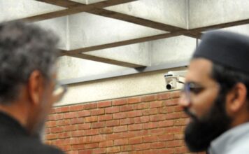 two commissioners speak at break while two Muslim attendees stand in the foreground