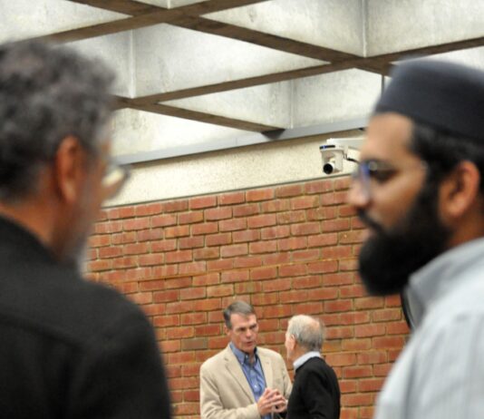 two commissioners speak at break while two Muslim attendees stand in the foreground