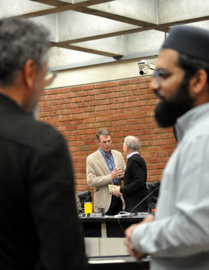 Hashing it out at break1 two commissioners speak at break while two Muslim attendees stand in the foreground
