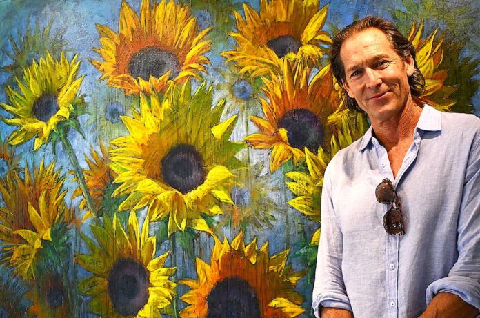 Gordon Smedt stands in front of his sold painting Happy Place Gordon Smedt with sunflower artwork