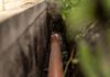 ORANGE PLASTIC This sewage pipe was laid inside a deep narrow trench along a concrete foundation wall. (Shutterstock)
