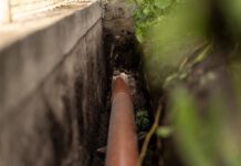 ORANGE PLASTIC This sewage pipe was laid inside a deep narrow trench along a concrete foundation wall. (Shutterstock)