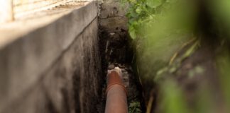 ORANGE PLASTIC This sewage pipe was laid inside a deep narrow trench along a concrete foundation wall. (Shutterstock)